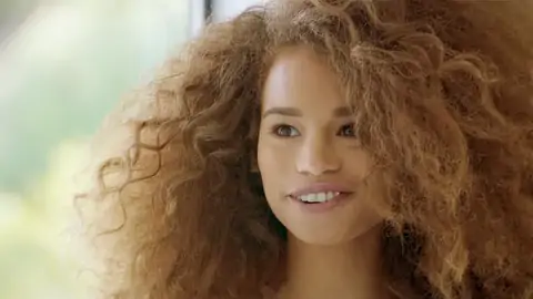 Nubile black with wavy hair is railing a thick rod on the bed